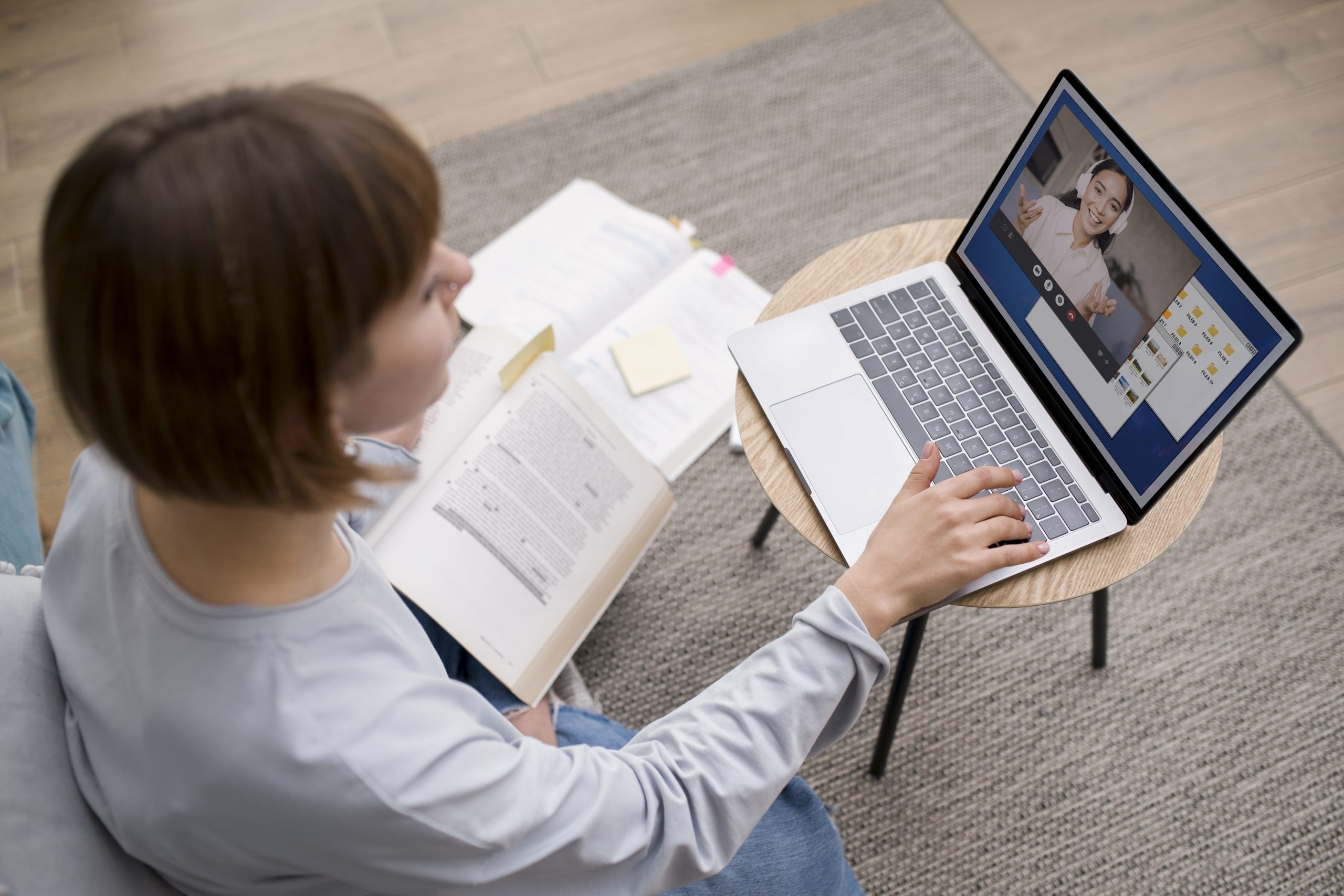 mulher assiste aula online em notebook a sua frente com livros no colo
